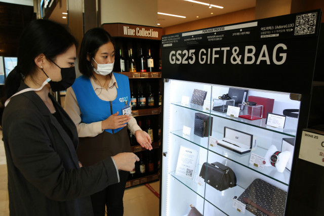 고객이 GS25 파르나스타워점에서 직원과 함께 명품 판매대를 살펴보고 있다. / 사진제공=GS25