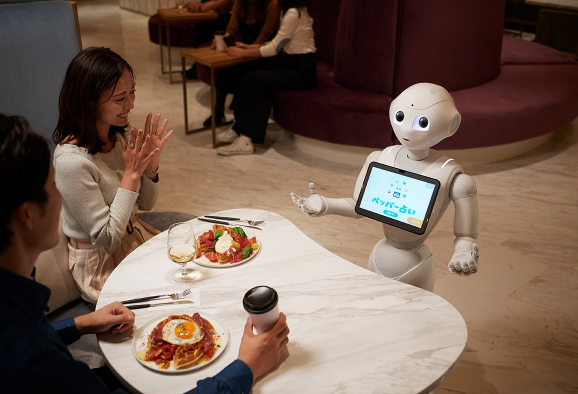 사진='Pepper'가 성별과 나이를 고객의 표정에서 읽을 각각에 맞는 추천 메뉴를 제안, 주문을 받고 고객과 합석하여 즐겁게 식사할 수 있도록 서비스를 제공 중이다.