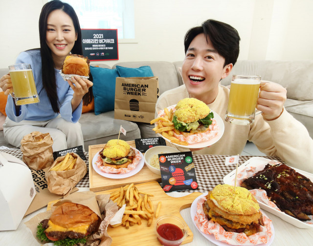 뉴욕아파트먼트 및 클래식햄버거에서 아메리칸 버거위크 행사 메뉴를 배달받은 부부가 집에서 수제버거와 맥주를 즐기고 있다
