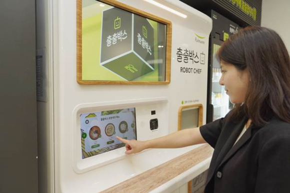 사진=풀무원 직원이 스마트 무인 즉석조리 자판기 ‘출출박스 로봇셰프’로 구매한 메뉴를 선보이고 있다.